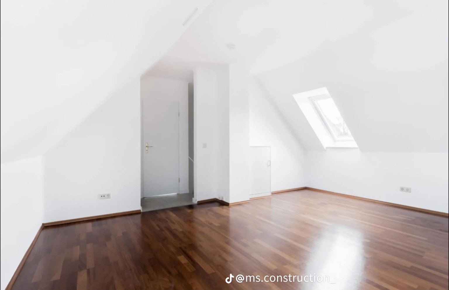Attic room with roof window and dark flooring